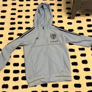 Adidas jacket with hoodie, light blue and has monogram on the front.